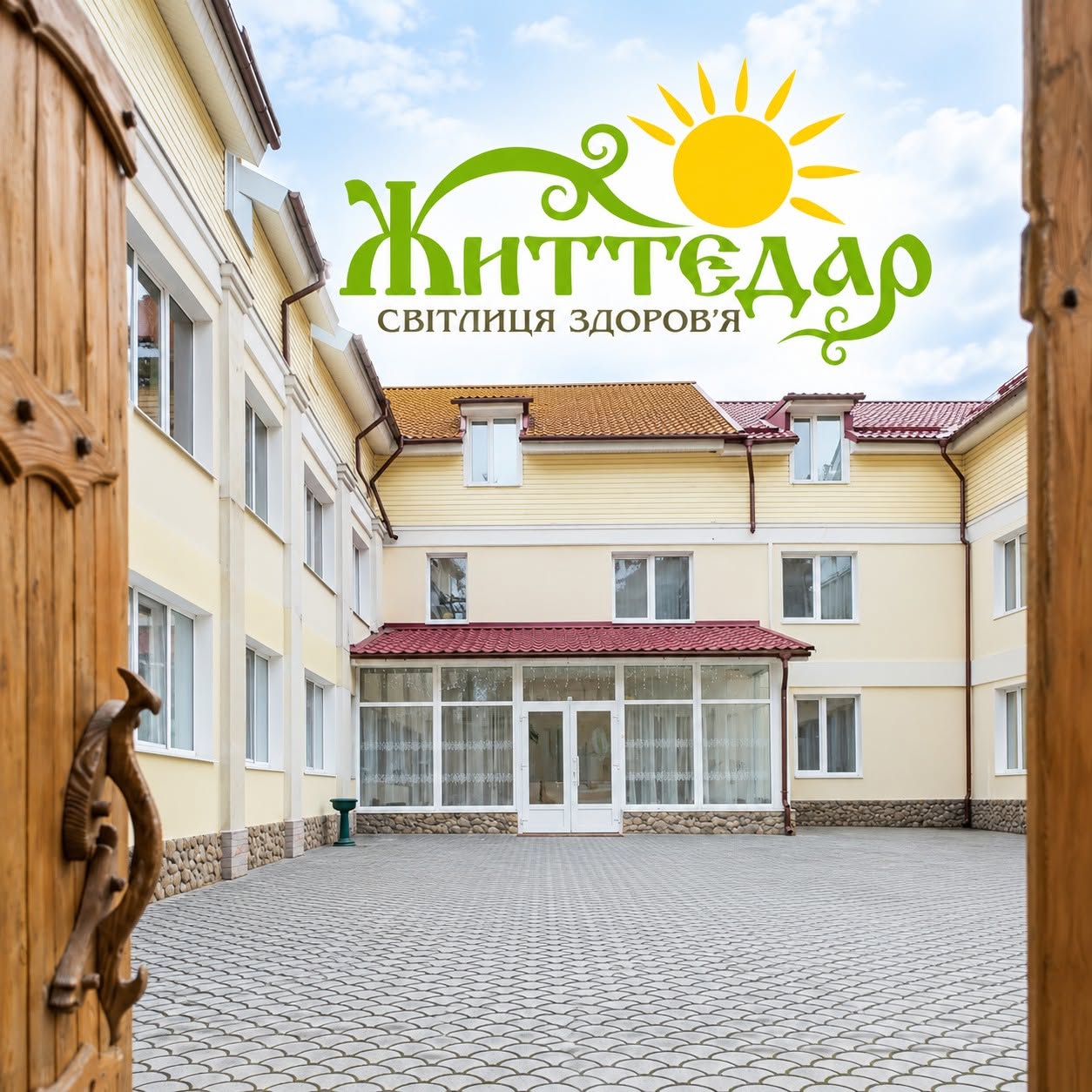 Фірмове зображення Життєдару: подвір’я між відчиненими дерев’яними дверима та логотип із сонцем